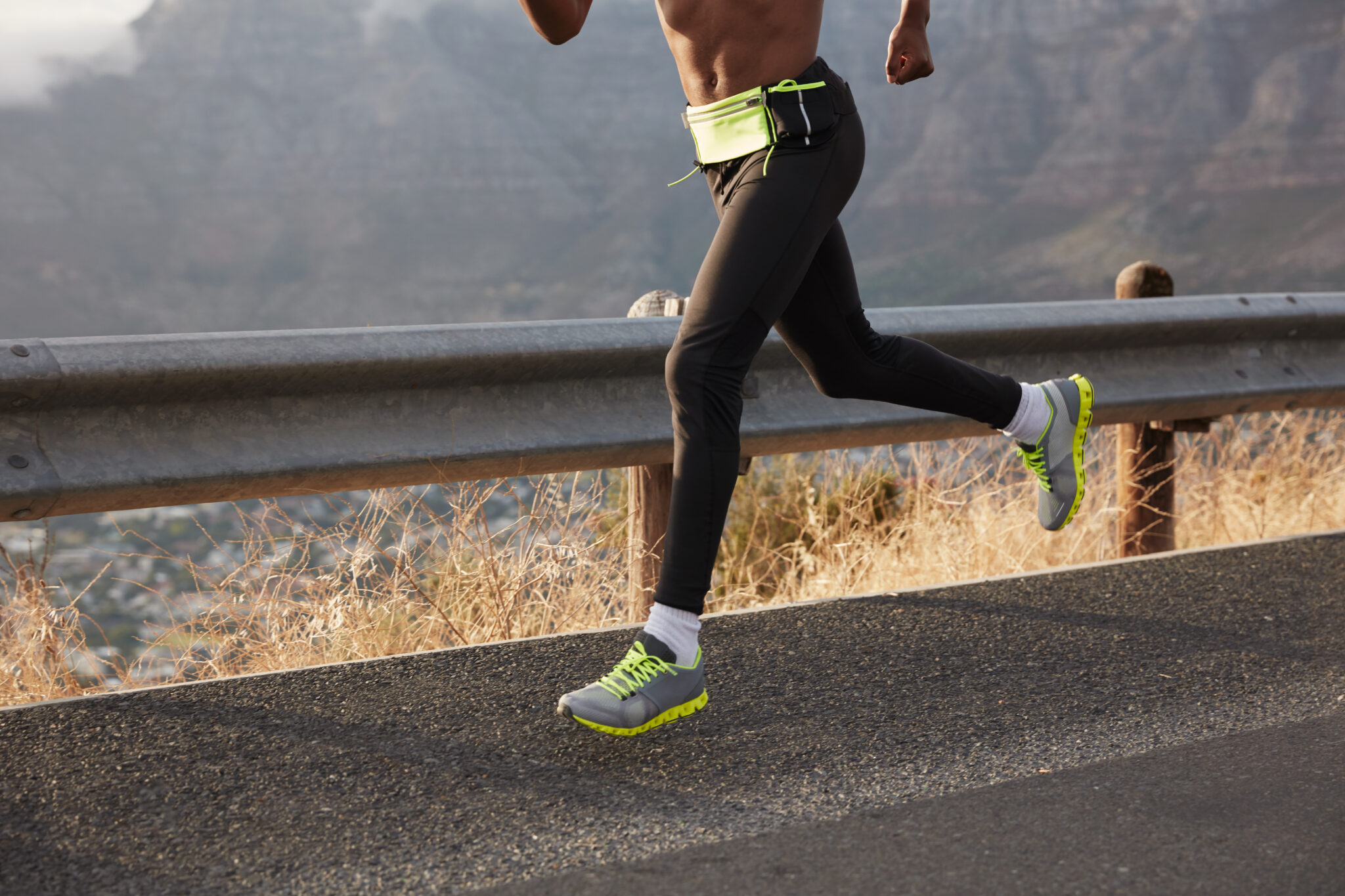 Cropped image of athlete runner runs on road, photographhed in motion, wears comfortable sneakers, takes part in maraphone. Focus on foot. Sportsman leads healthy lifestyle, covers destination